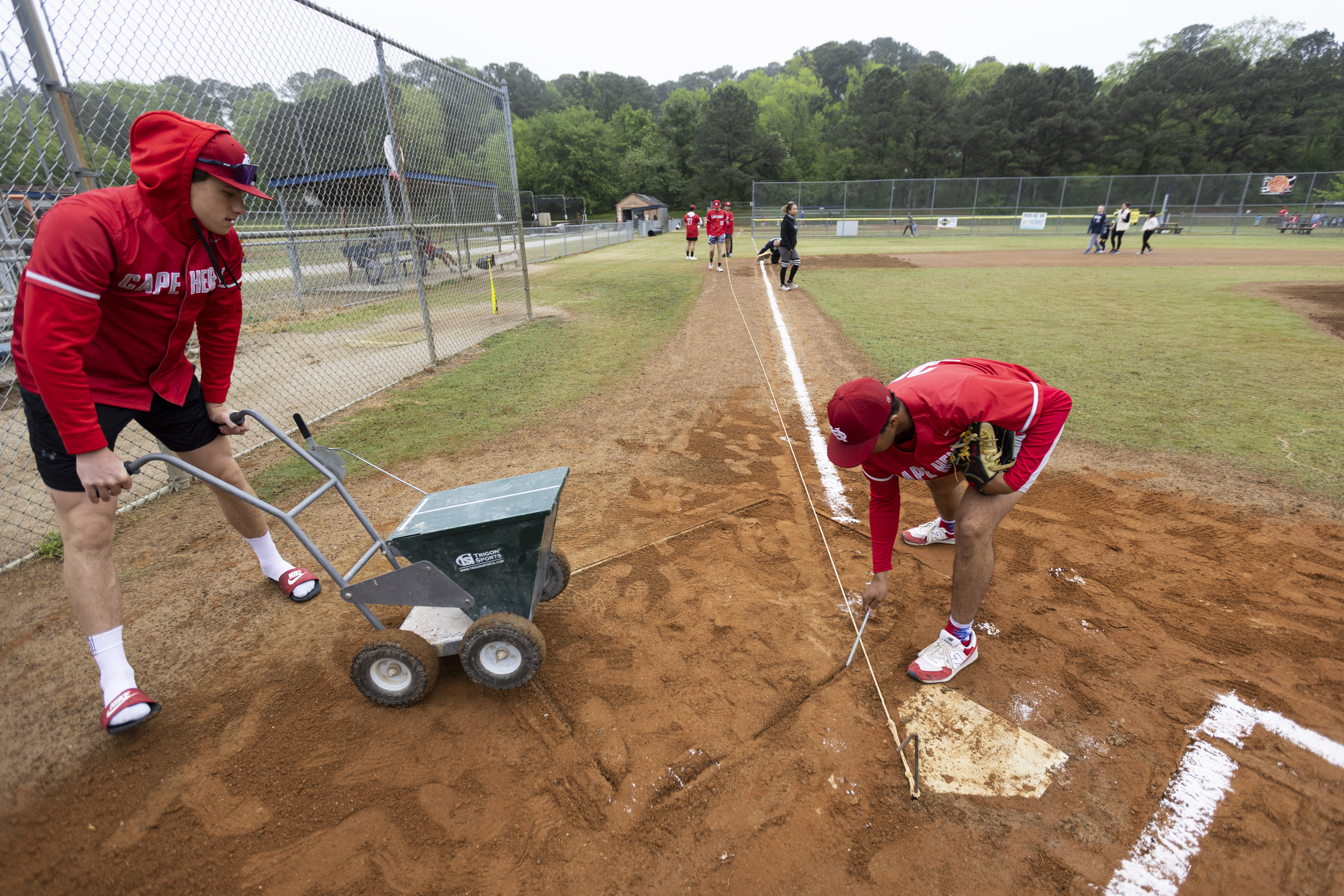 Cape Henry Collegiate players paint lines around home plate in...